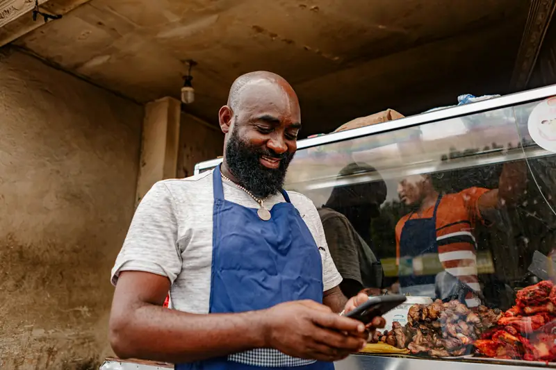Comerciante sorrindo usando o celular na loja