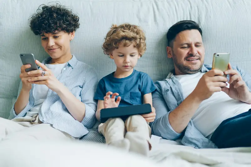 Família no sofá usando celulares e tablet